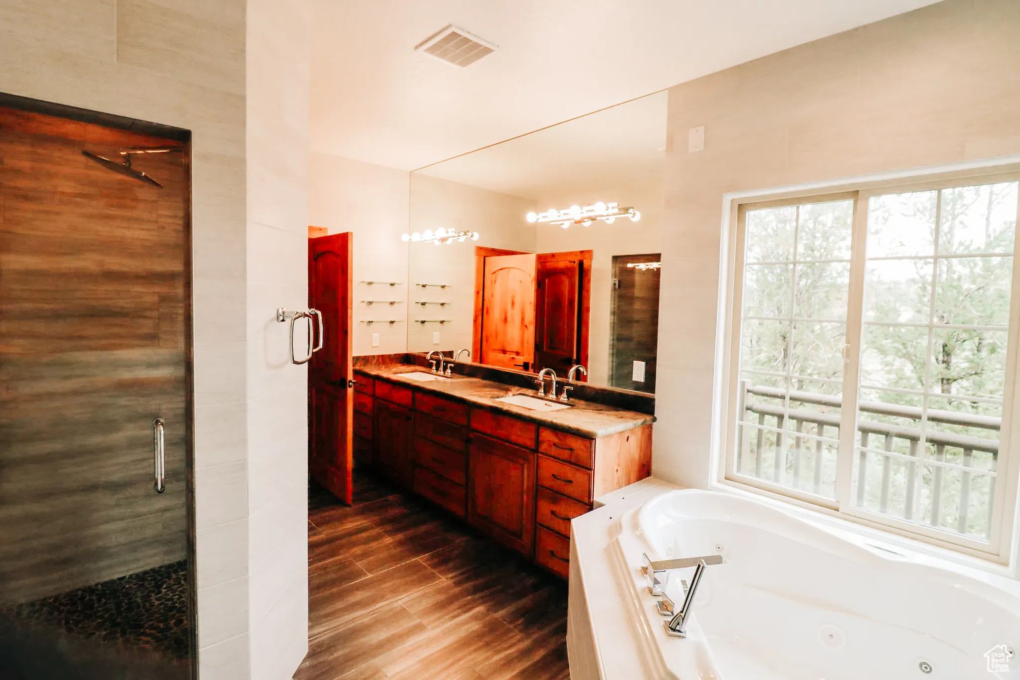 Full bathroom featuring double vanity, a whirlpool tub, dark wood-style floors, and a shower stall