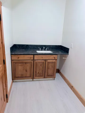 Wood-finish vanity with a dark countertop and an undermount sink