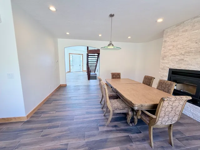 Interior space featuring wood-finish flooring, a stone-accented fireplace, and an arched doorway