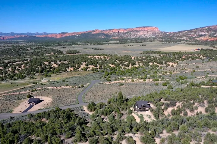 Expansive landscape featuring distant red rock formations and multiple properties nestled among natural vegetation