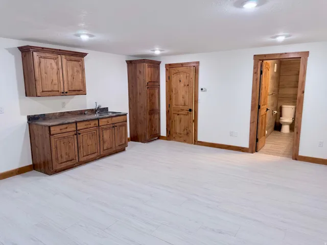 Wet bar area featuring wood cabinetry, stone-look countertop, and stainless steel sink