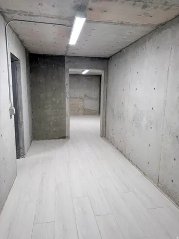 Concrete walls and ceiling featuring exposed conduit with overhead linear lighting
