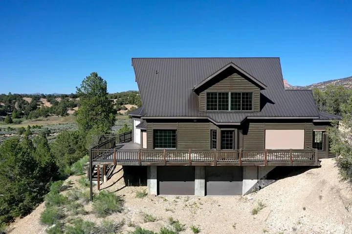 Log-sided residence featuring a dark metal roof and an expansive wood deck