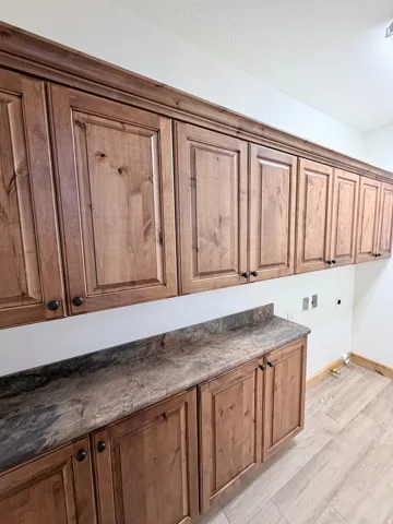 Extensive custom cabinetry with crown molding, durable stone-finish countertops, and light wood-finish flooring