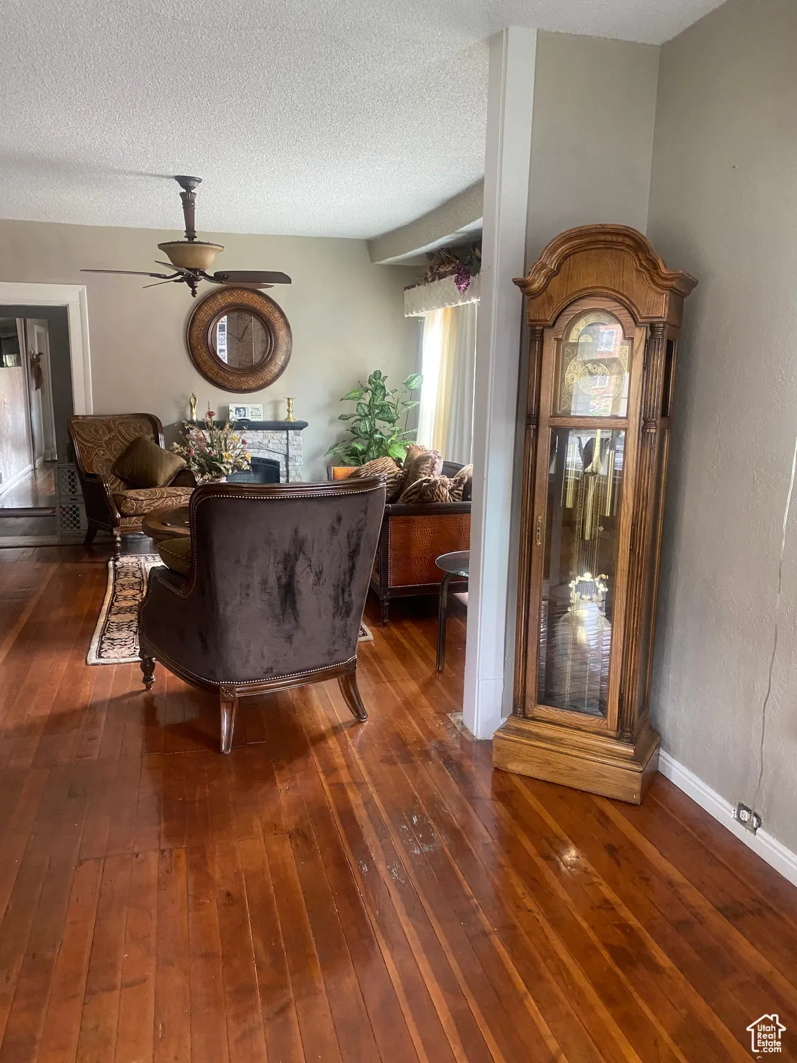 Living room featuring a textured ceiling, wood-type flooring, and a ceiling fan
