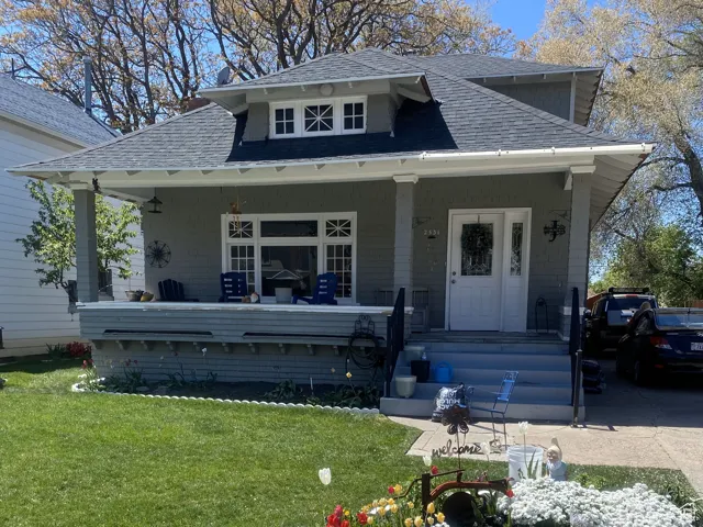 Bungalow with covered porch, roof with shingles, and a front lawn
