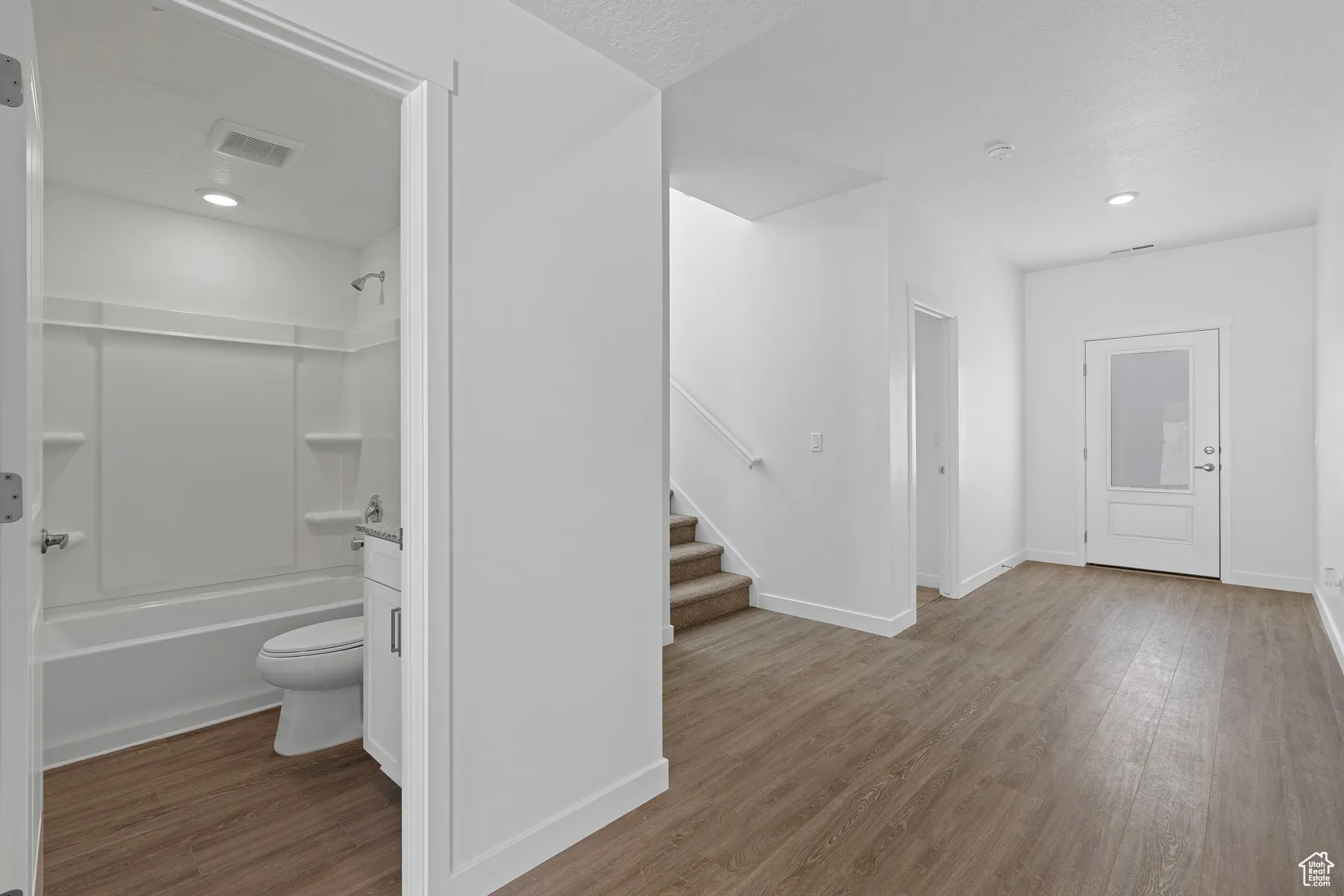 Interior space with wood finished floors, stairs, visible vents, baseboards, and recessed lighting