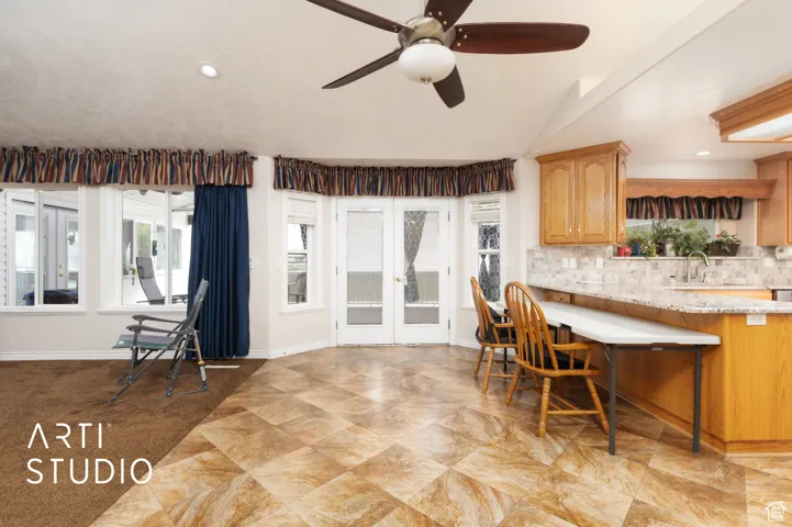 Kitchen featuring healthy amount of natural light, a breakfast bar, recessed lighting, decorative backsplash, and french doors