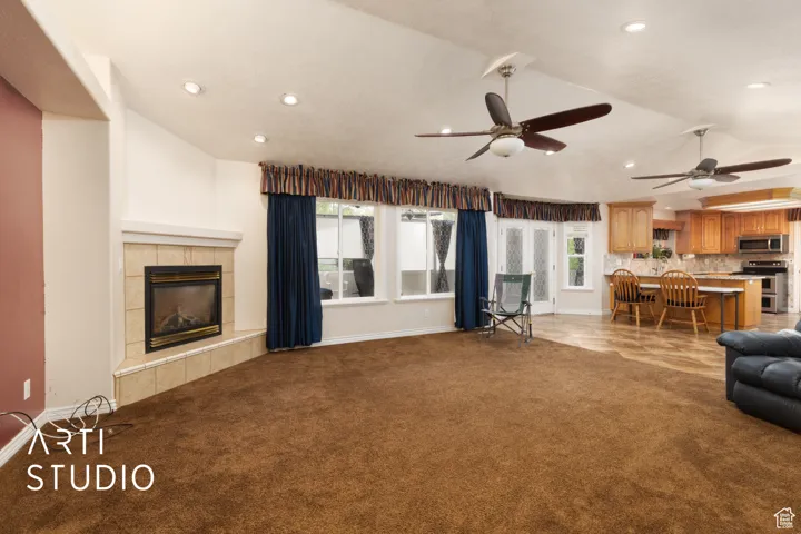 Living area with light carpet, a fireplace, ceiling fan, and recessed lighting