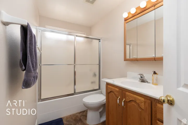 Full bath featuring vanity and shower / bath combination with glass door