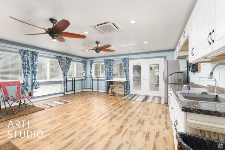 Kitchen featuring white cabinetry, light wood finished floors, a ceiling fan, freestanding refrigerator, and french doors