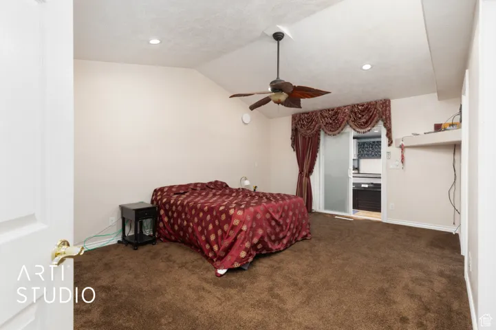 Bedroom featuring dark colored carpet, vaulted ceiling, ceiling fan, recessed lighting, and ensuite bathroom