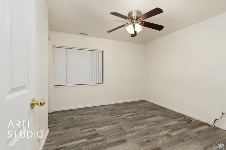 Unfurnished room with baseboards, visible vents, and dark wood-type flooring