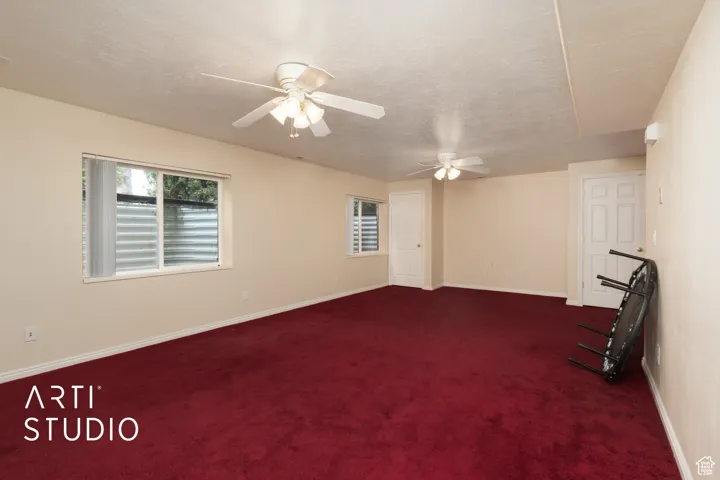 Spare room with dark colored carpet, a textured ceiling, and ceiling fan