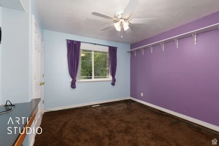 Spare room featuring dark carpet, a textured ceiling, and ceiling fan