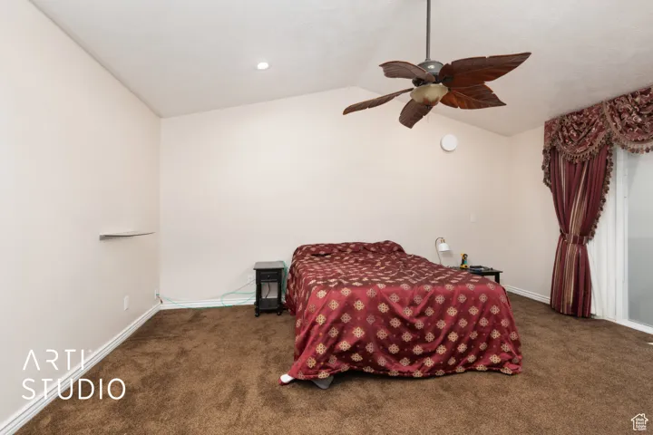 Carpeted bedroom featuring vaulted ceiling and ceiling fan