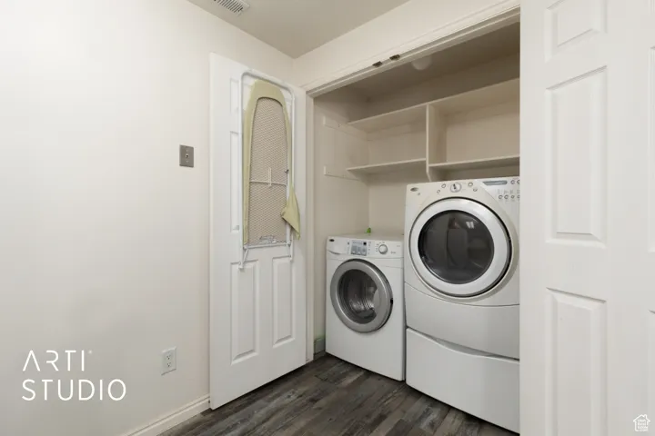Washroom featuring separate washer and dryer, laundry area, dark wood-style flooring, and baseboards