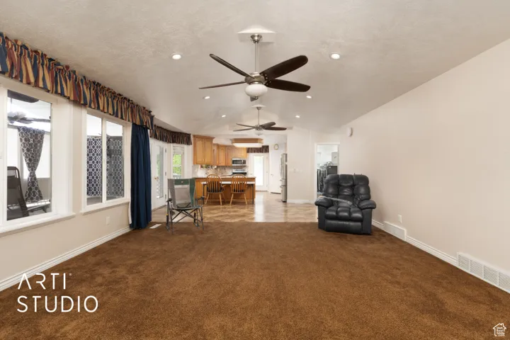Sitting room with light colored carpet, a textured ceiling, vaulted ceiling, recessed lighting, and a ceiling fan