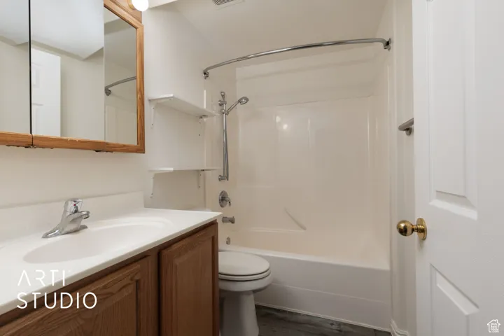 Bathroom featuring toilet, visible vents, vanity, bathtub / shower combination, and wood finished floors