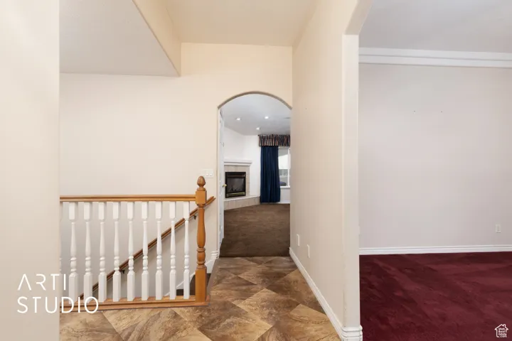 Hallway with arched walkways, dark colored carpet, an upstairs landing, and recessed lighting