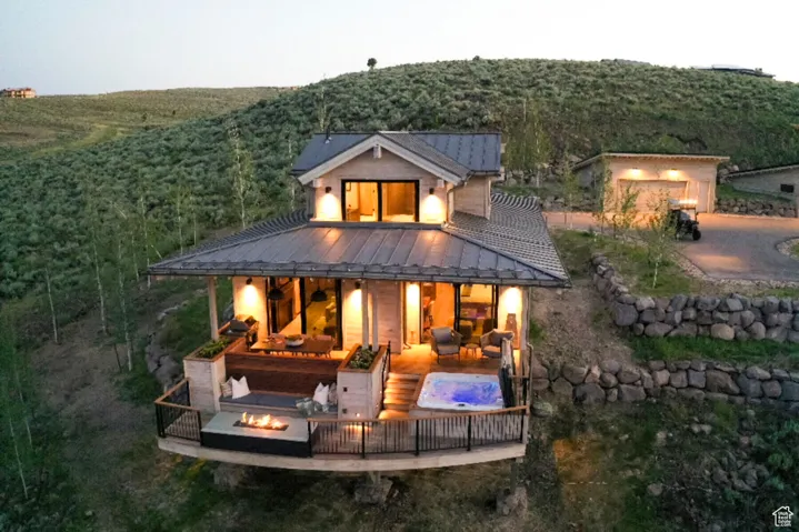 Back of house with a forest view, a standing seam roof, metal roof, and an outdoor living space with a fire pit