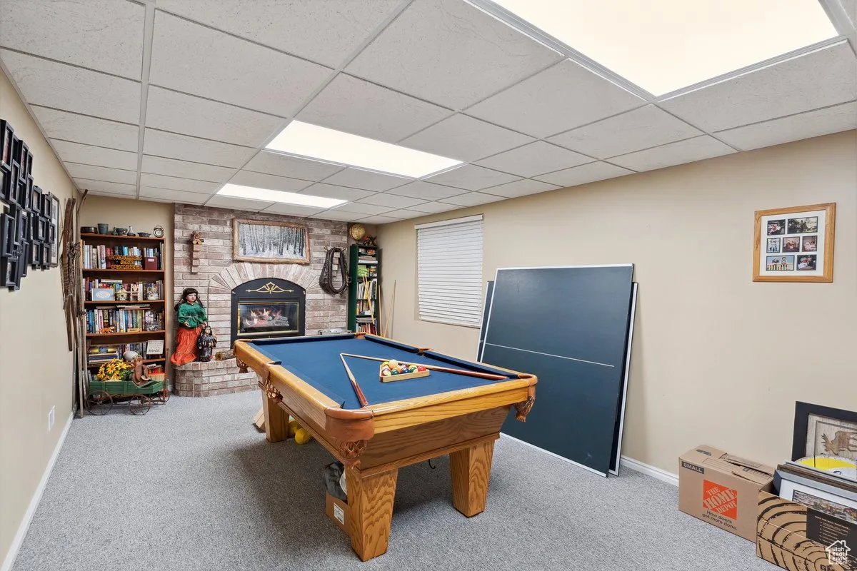 Game room with carpet floors, a fireplace, a paneled ceiling, pool table, and baseboards