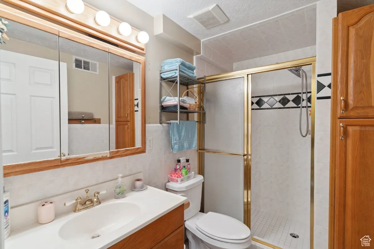 Full bath with a shower stall, vanity, toilet, and tile walls