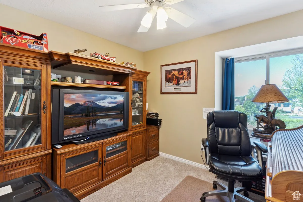 Office area with light carpet, a ceiling fan, and baseboards