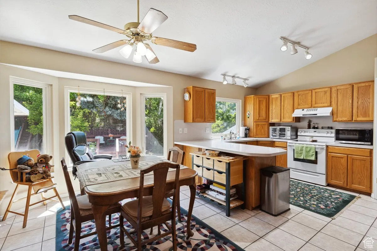 Kitchen with white electric range, under cabinet range hood, stainless steel microwave, rail lighting, and light countertops