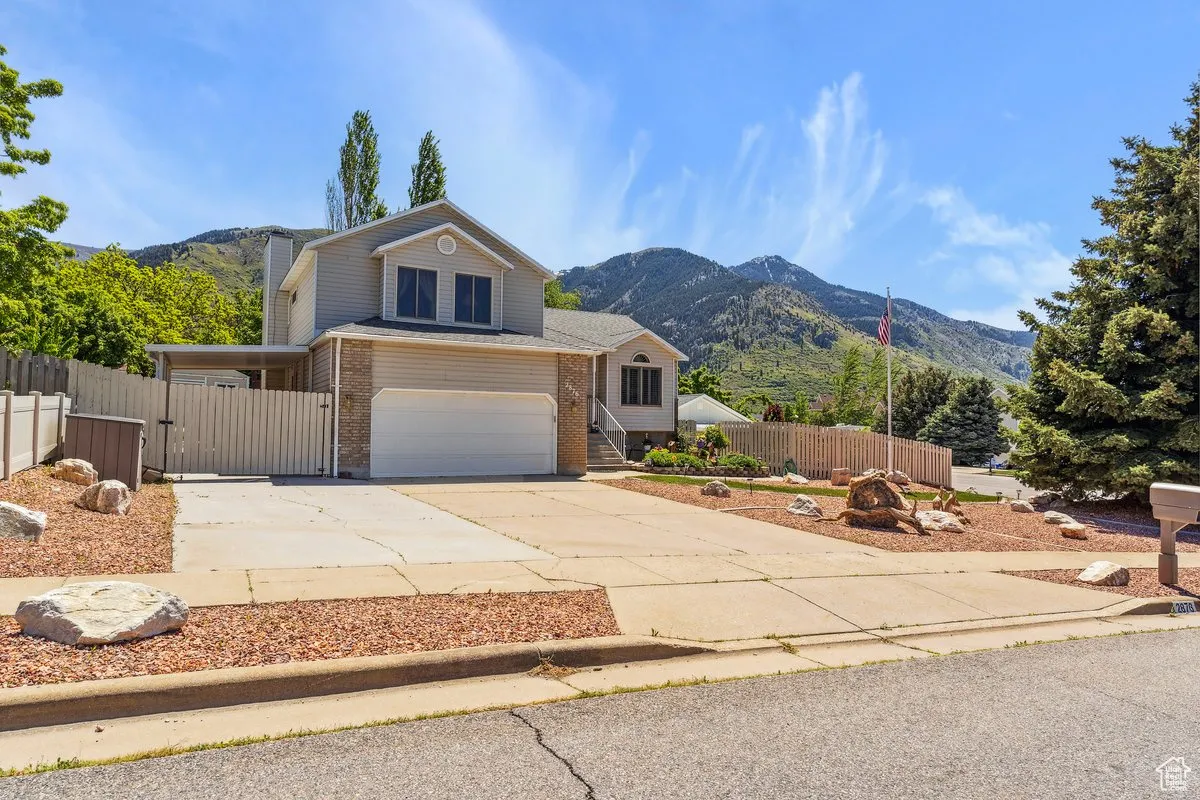 View of front of property featuring brick siding, driveway, a garage, a mountain view, and fence