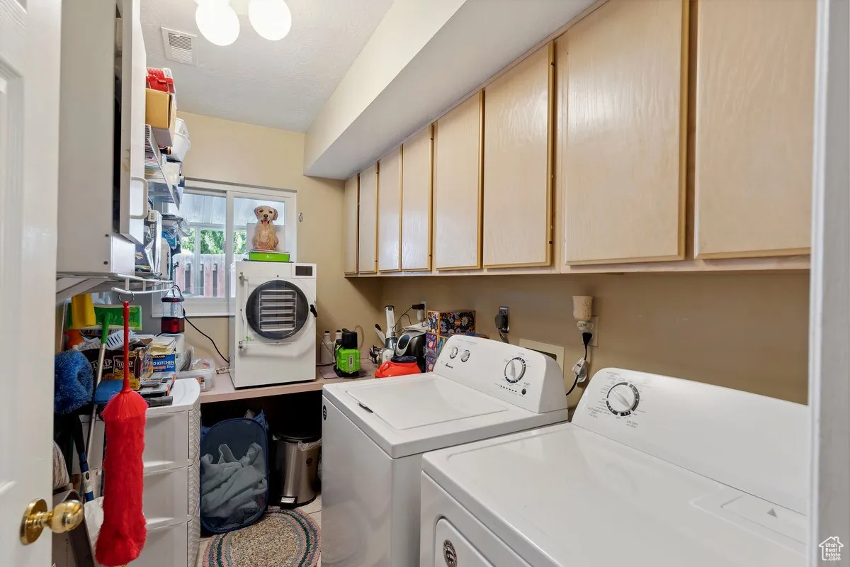 Laundry room with washer and clothes dryer, cabinet space, and a textured ceiling