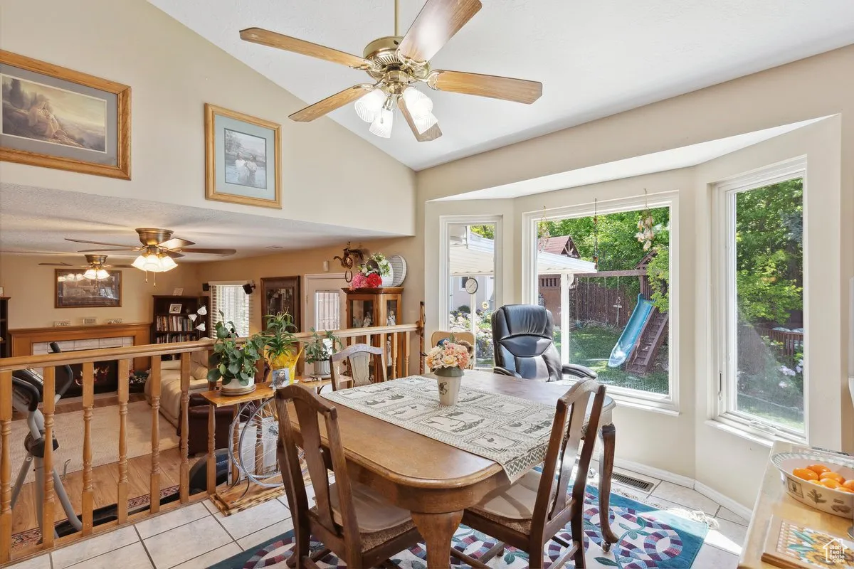 Dining space featuring lofted ceiling, a ceiling fan, light tile patterned floors, and plenty of natural light