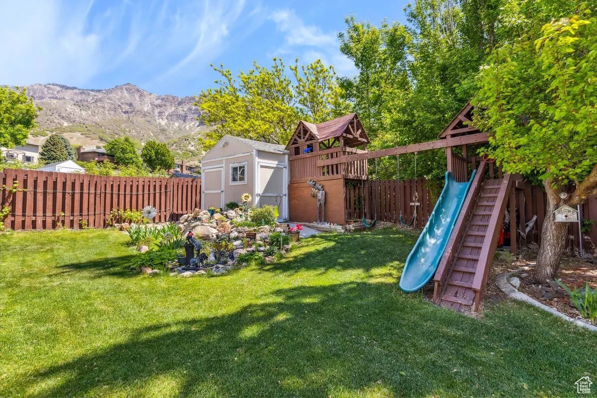 View of yard featuring a storage shed, a playground, an outbuilding, and a mountain view