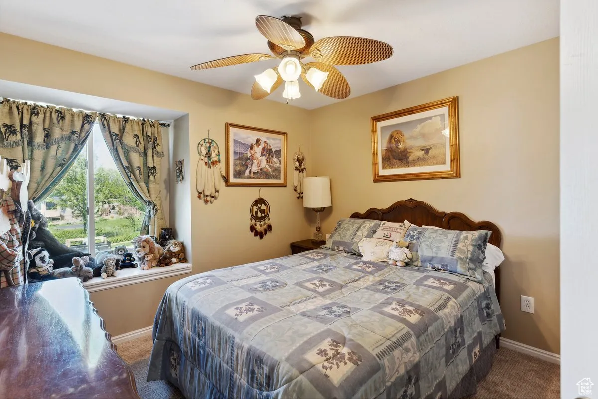 Carpeted bedroom with a ceiling fan and baseboards