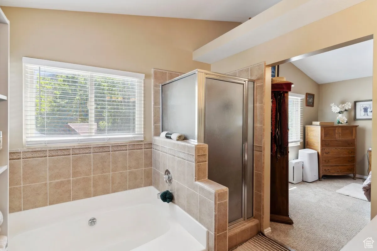 Full bathroom featuring a stall shower, a bath, and vaulted ceiling