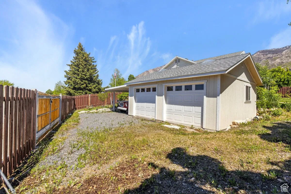 View of property exterior featuring a fenced backyard, roof with shingles, and a detached garage