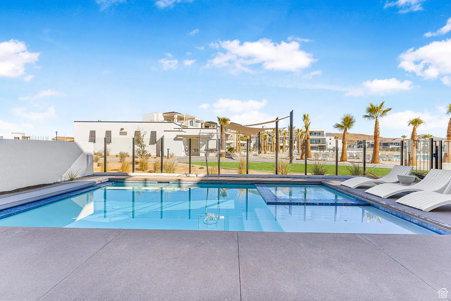 View of pool featuring a residential view, a pool with connected hot tub, and fence