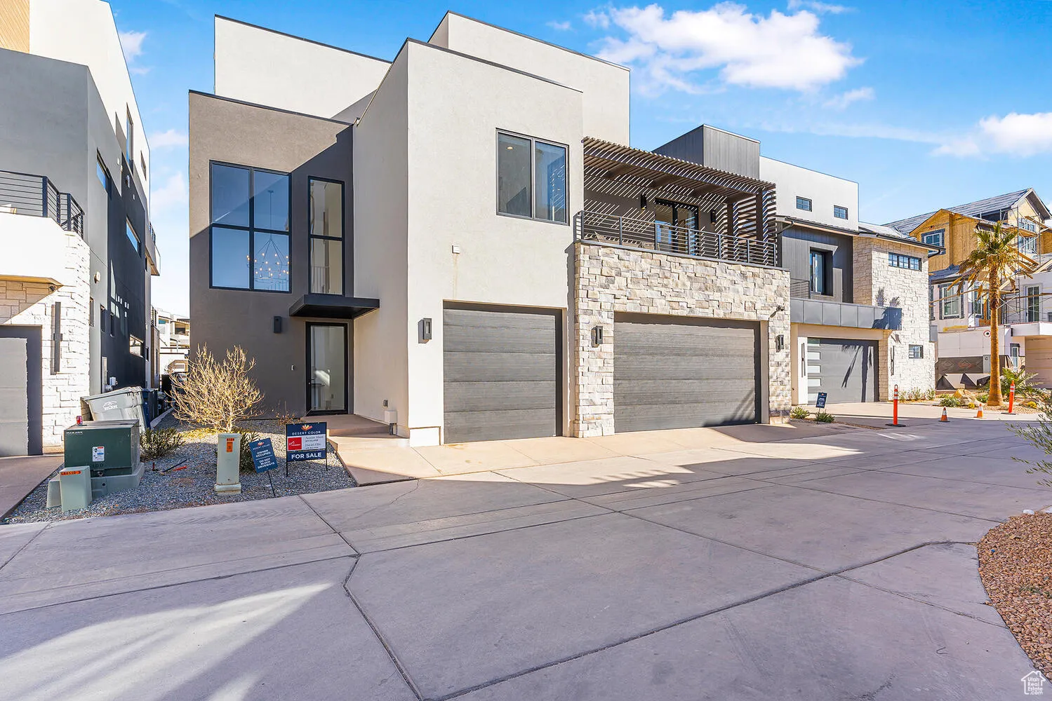 Modern home featuring stucco siding, a balcony, an attached garage, and a residential view