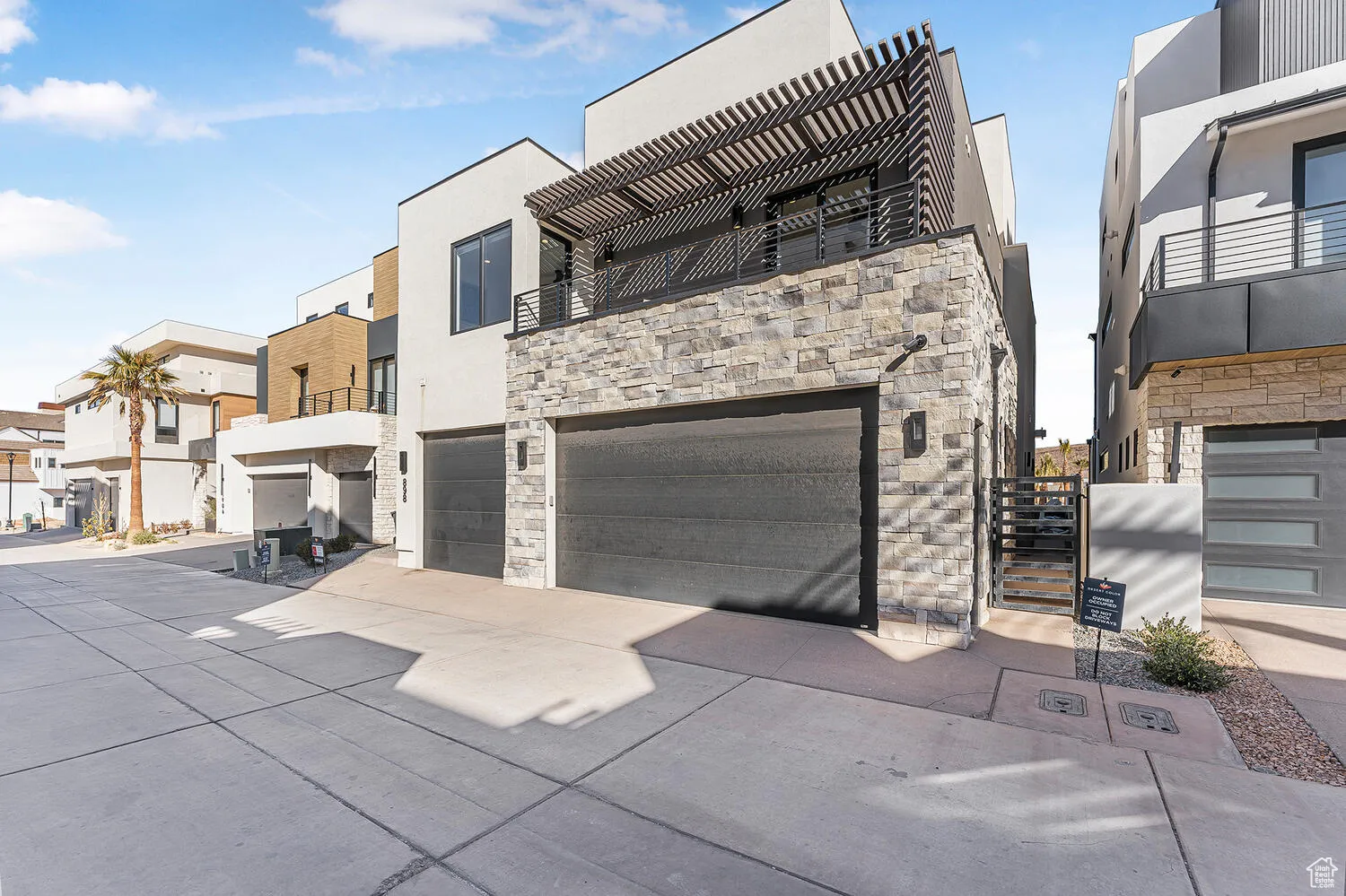 View of front of property with a garage, stone siding, stucco siding, and a residential view