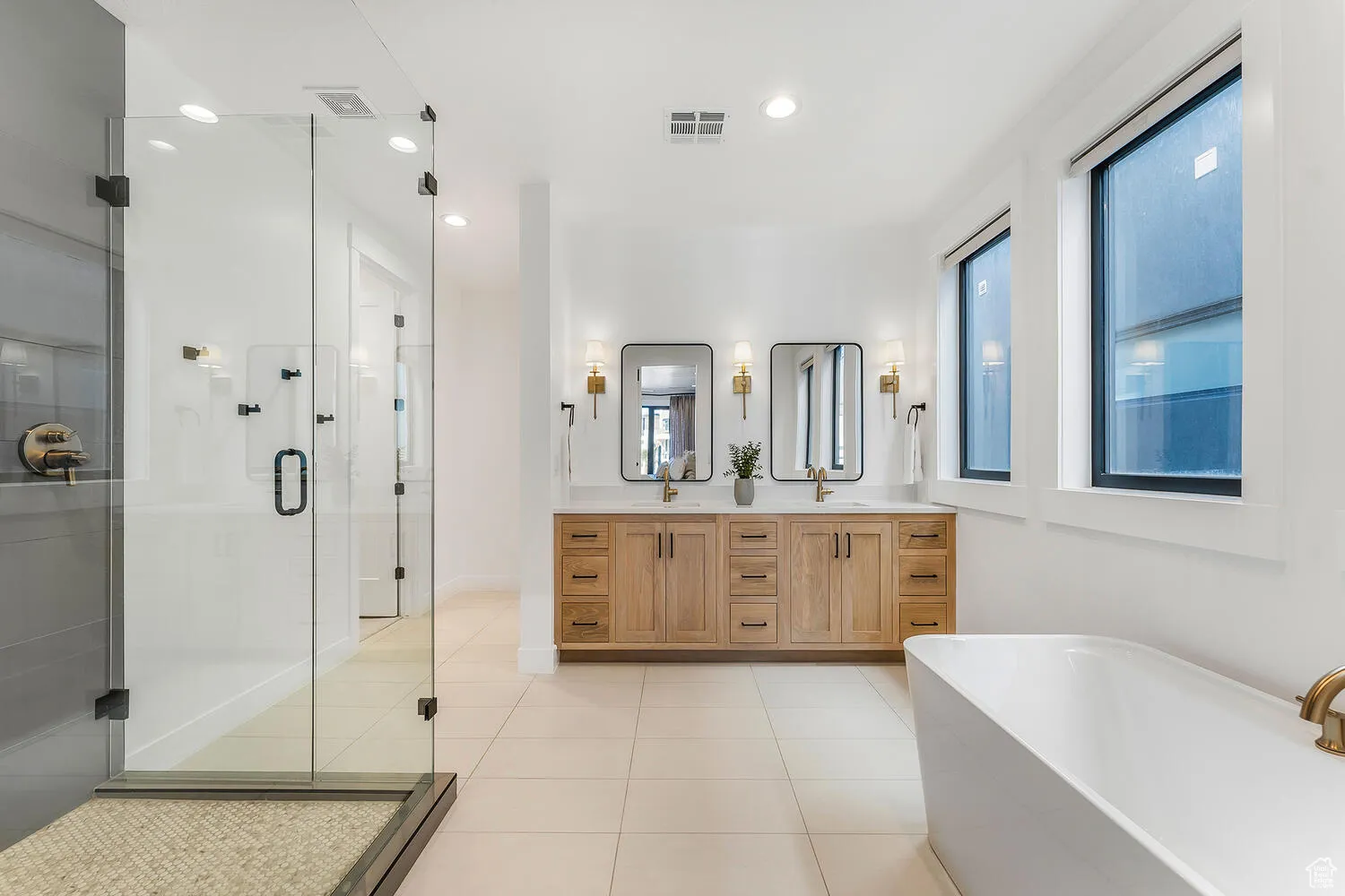 Full bath with double vanity, tile patterned flooring, a stall shower, a freestanding tub, and recessed lighting