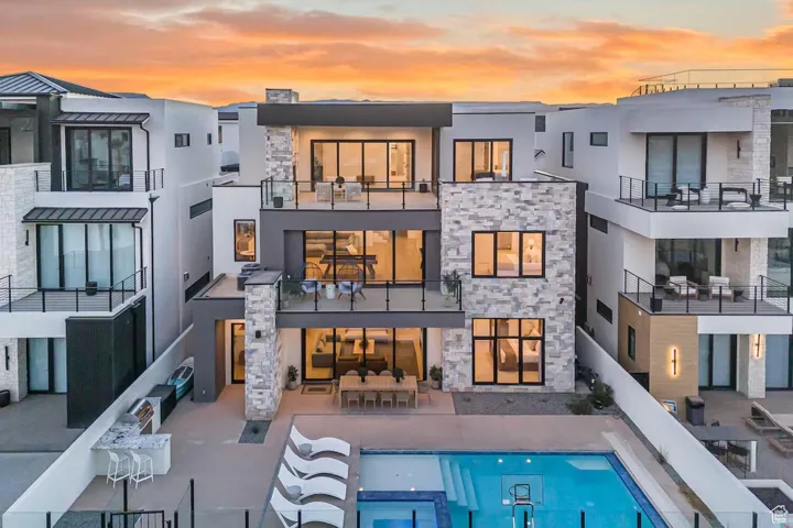 Rear view of house featuring stone siding, stucco siding, and a pool with connected hot tub