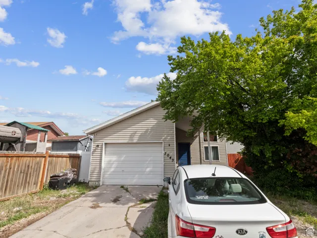 View of front of home featuring concrete driveway, an attached garage, and fence