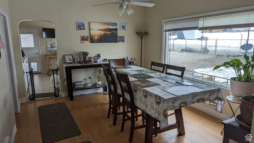 Dining room with arched walkways, a ceiling fan, wood finished floors, and a wealth of natural light
