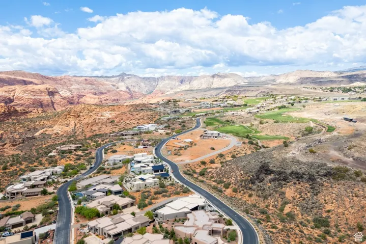 Aerial view of property and surrounding area featuring a mountainous background and nearby suburban area