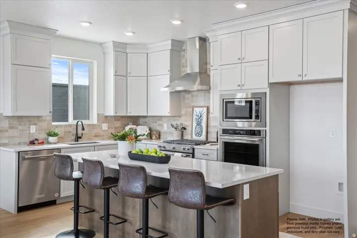 Kitchen with stainless steel appliances, a center island, a breakfast bar area, light stone countertops, and light wood finished floors