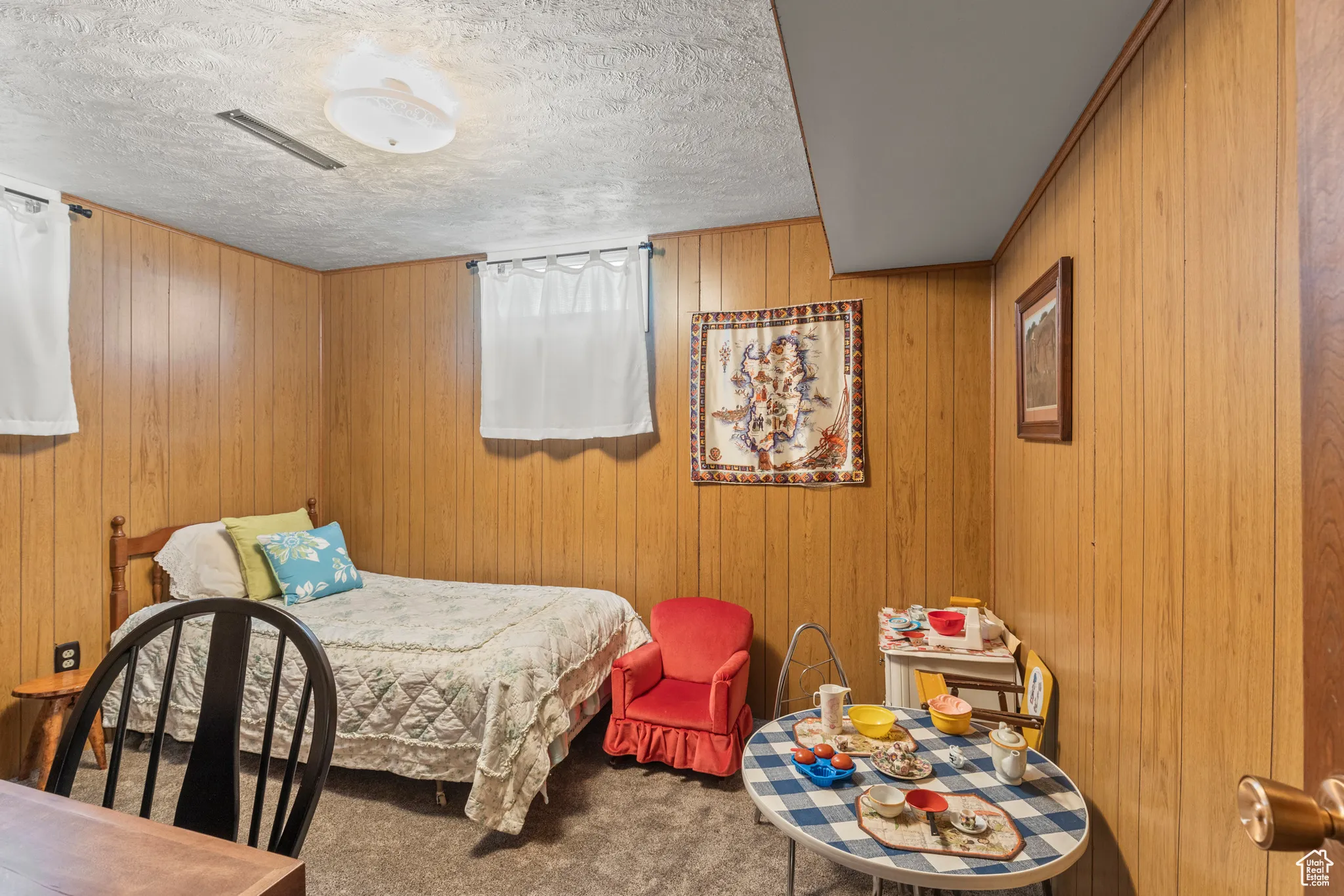 Carpeted bedroom featuring a textured ceiling and wooden walls
