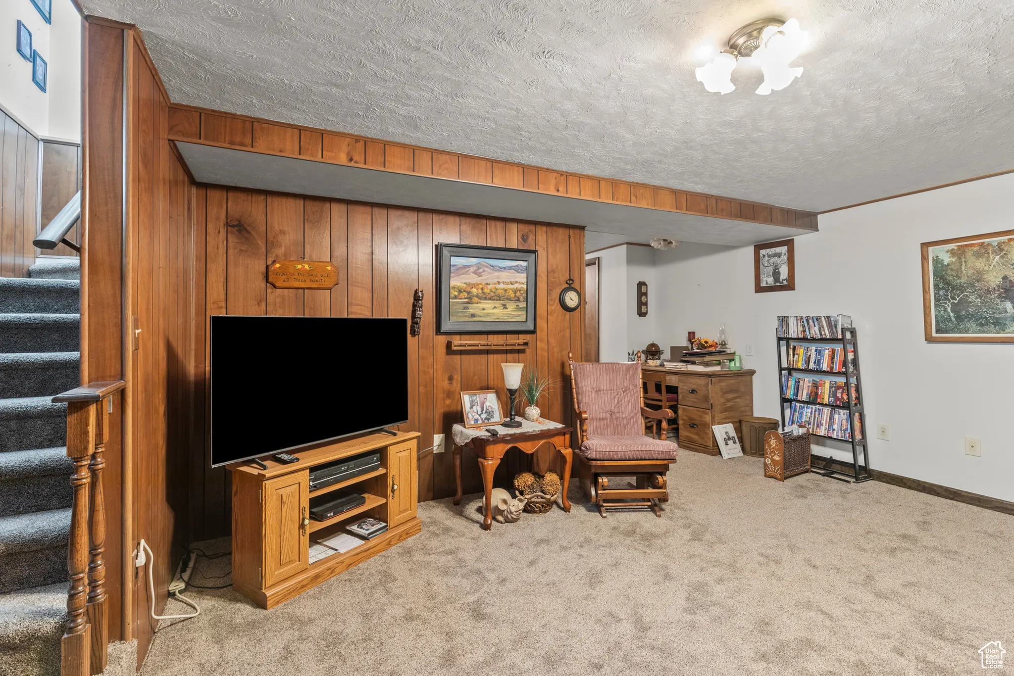 Living area with stairway, carpet floors, wood walls, a textured ceiling, and baseboards