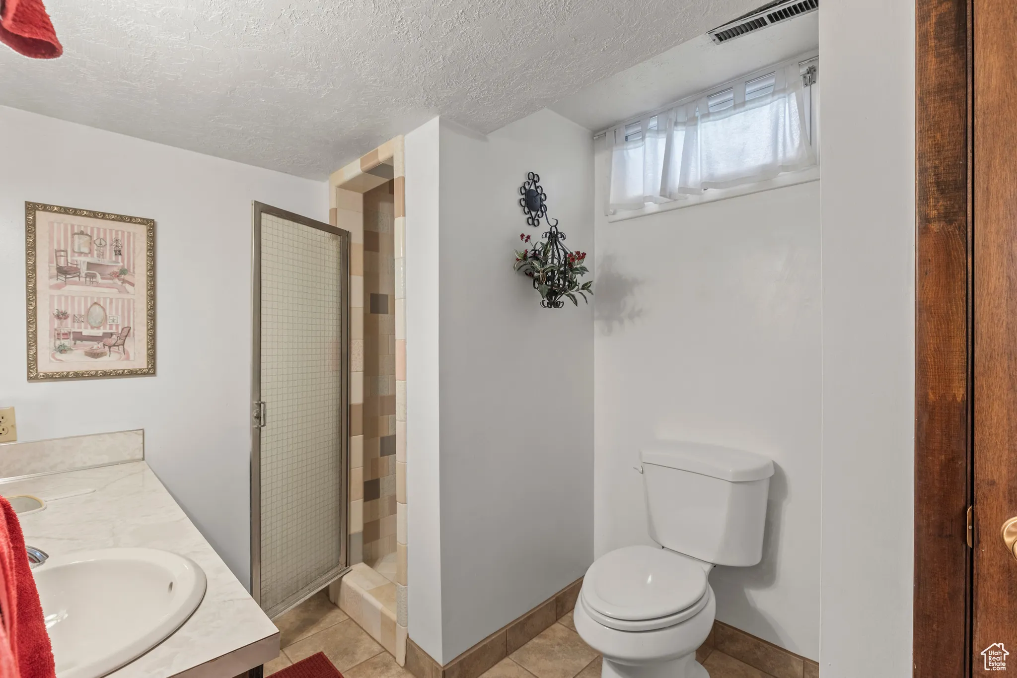 Bathroom featuring toilet, a stall shower, a textured ceiling, vanity, and tile patterned flooring