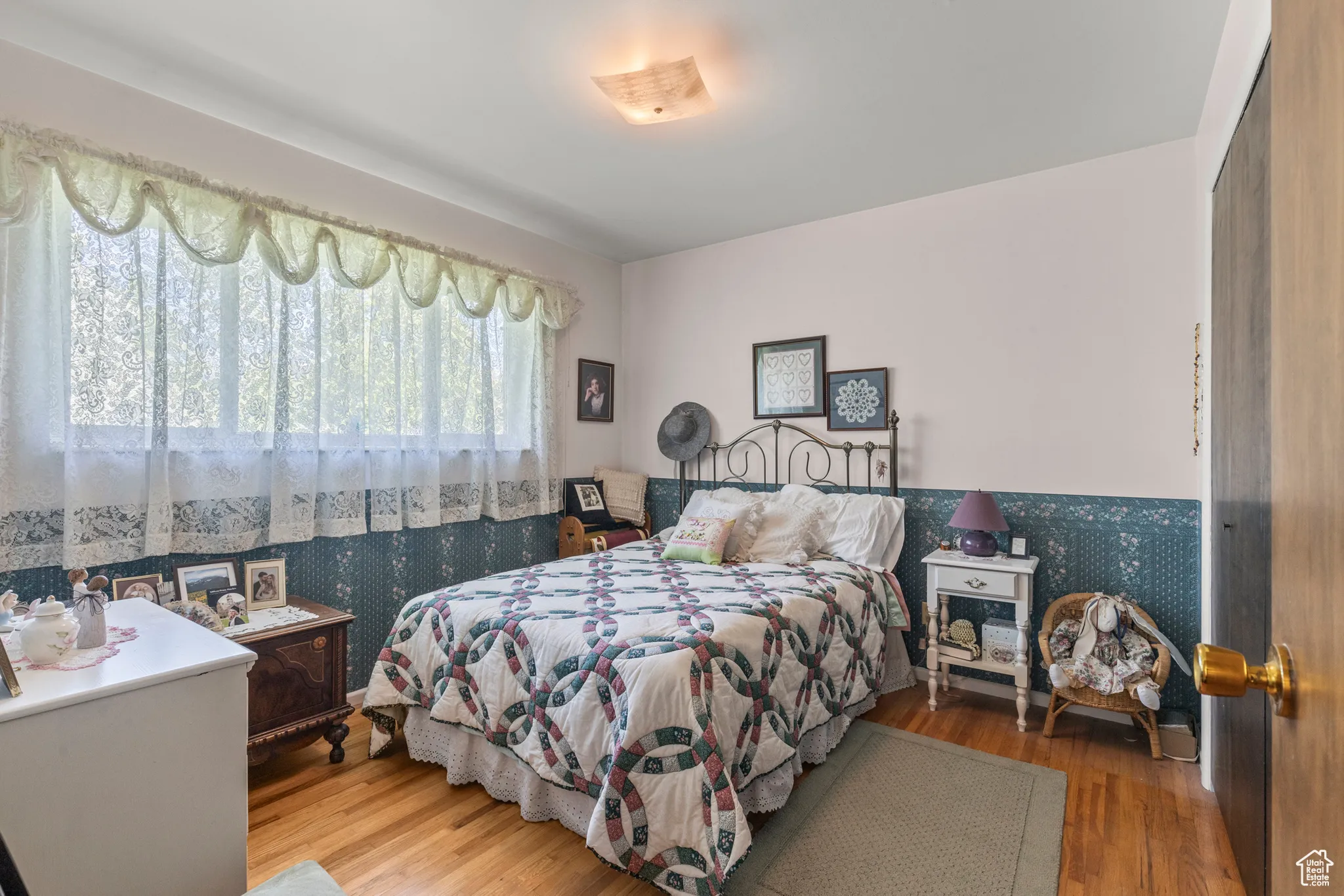 Bedroom featuring wallpapered walls, wood finished floors, and wainscoting
