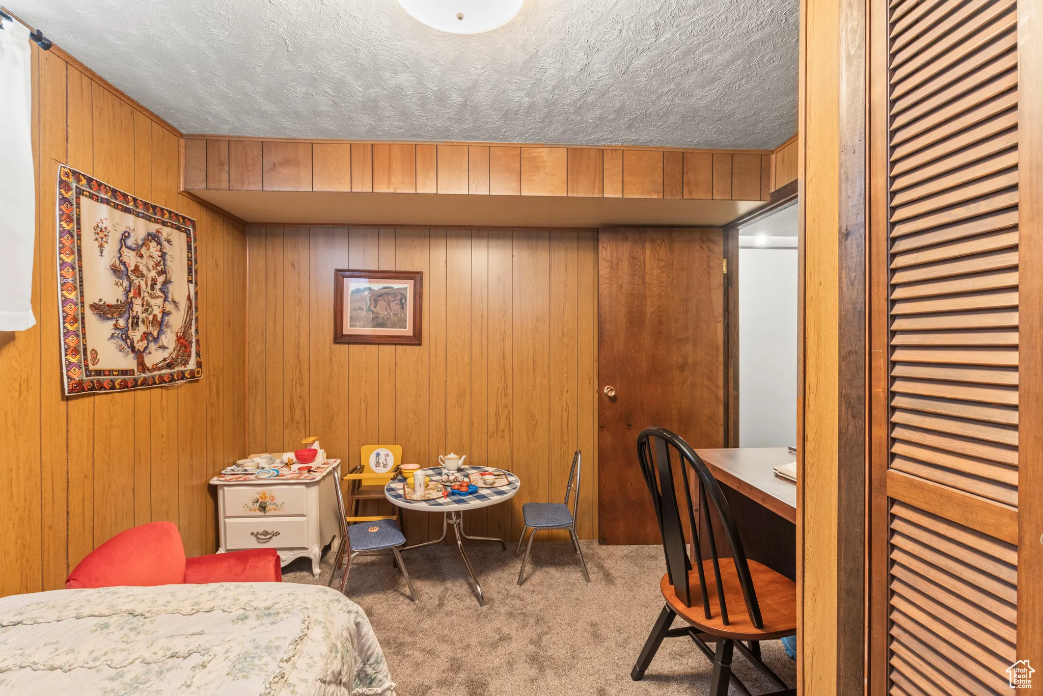 Carpeted bedroom featuring wooden walls and a textured ceiling